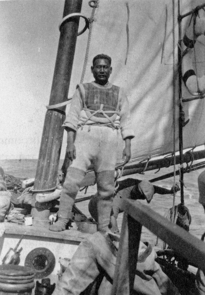 Image of a diver standing on a boat, getting ready to put on the dive suit. 